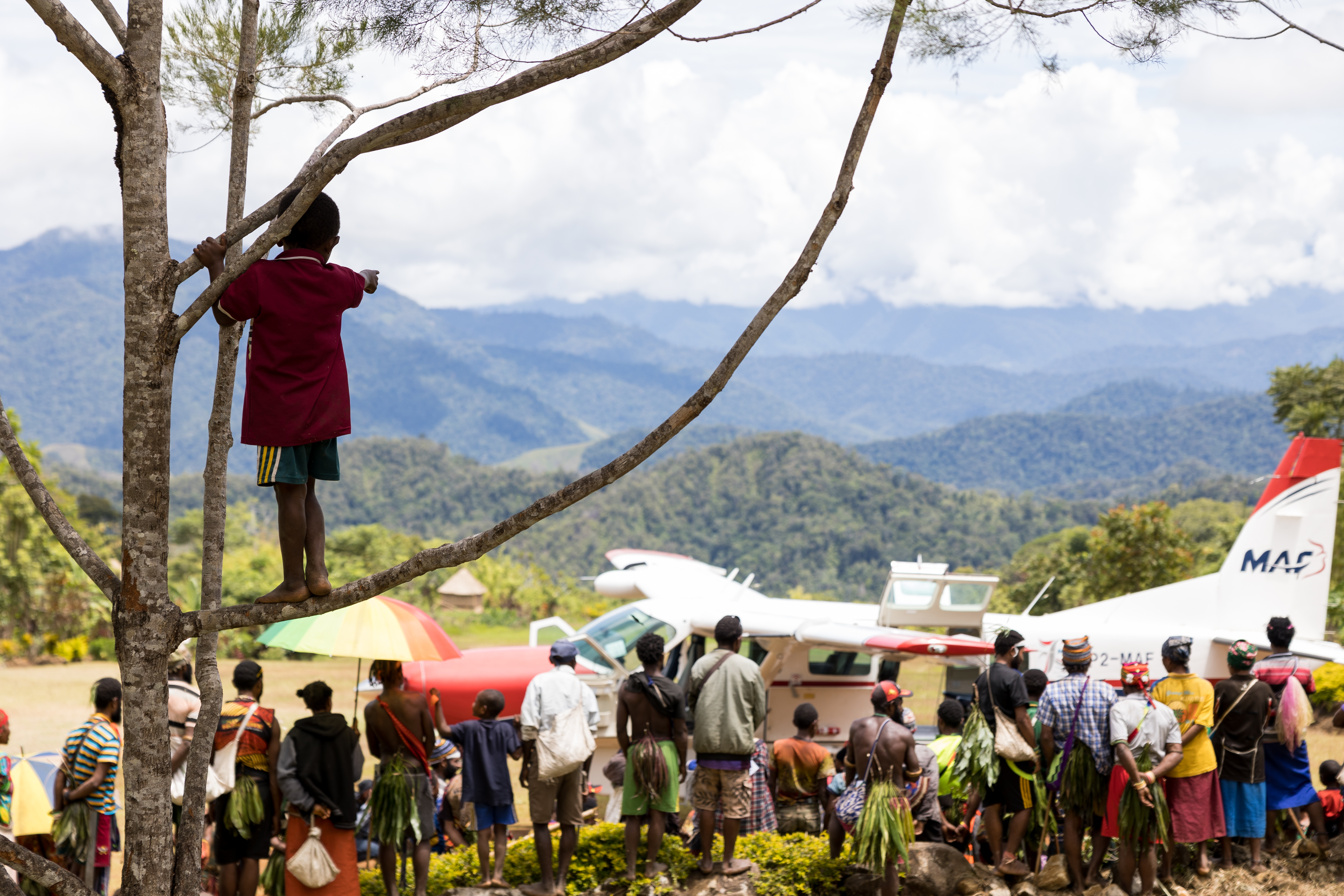 Papua bewoners kijken naar een aankomend MAF vliegtuig