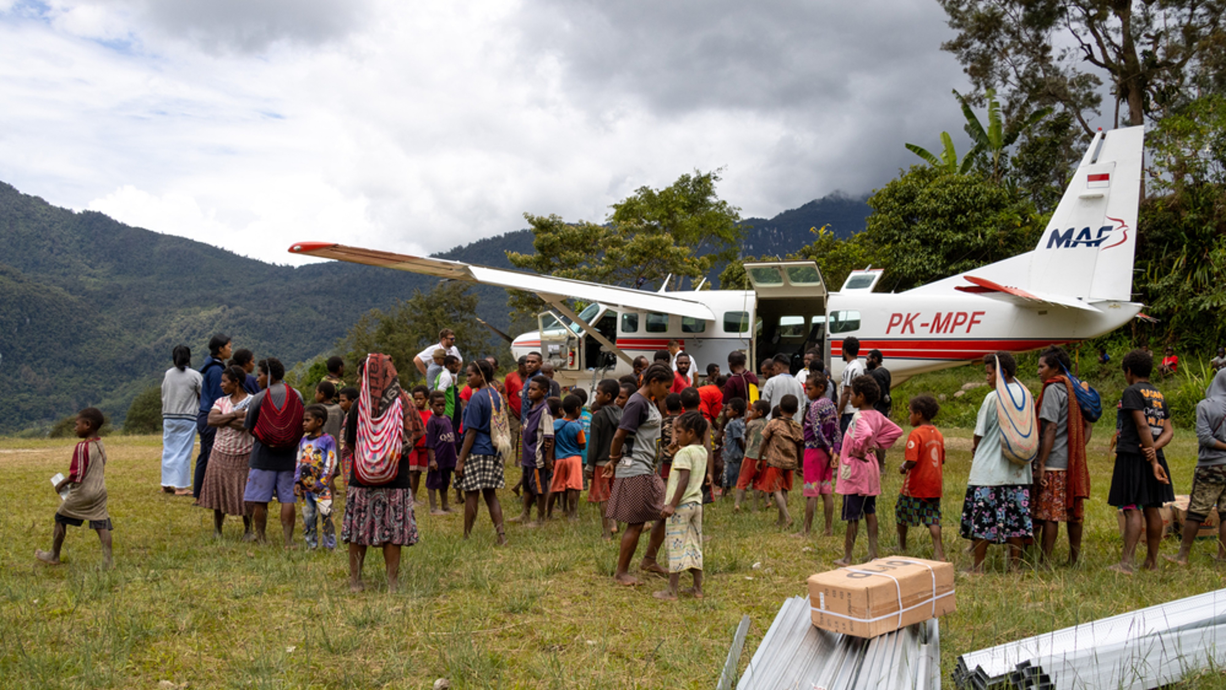 MAF airplane PK-MPF surrounded by Papua villagers at a delivery